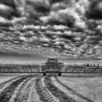 A tractor pulling a harrow bar across a field for spring preparation in rural dramatic black and white landscape